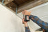 Person using a cordless drill to install an UnderDeck Shield panel.