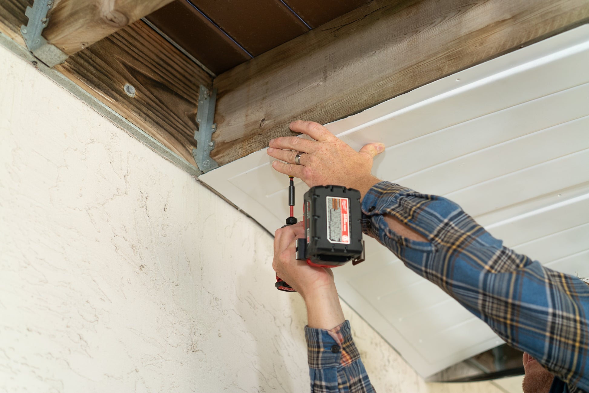 Person using a cordless drill to install an UnderDeck Shield panel.