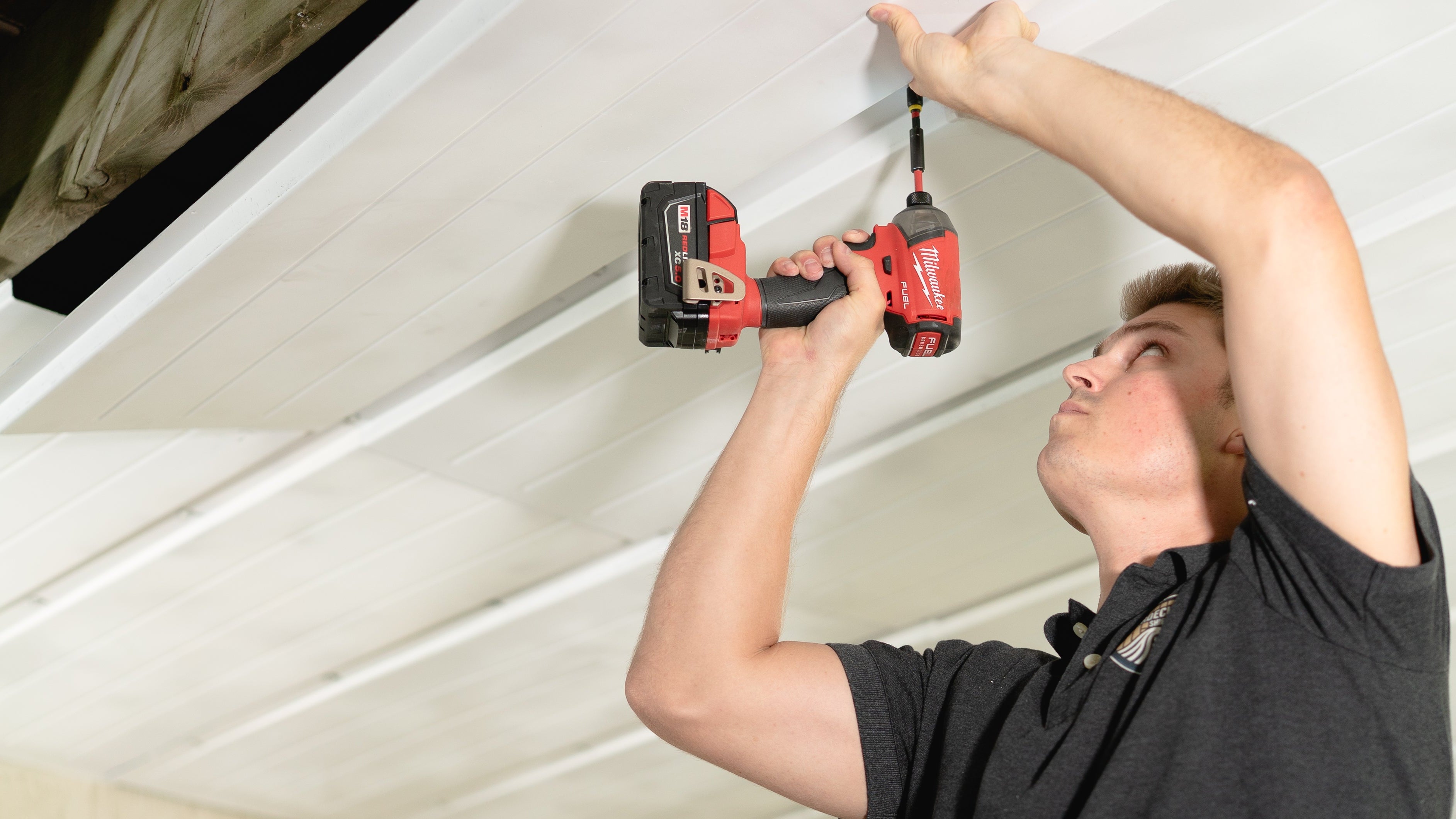 Person using a cordless drill to install an UnderDeck Shield panel