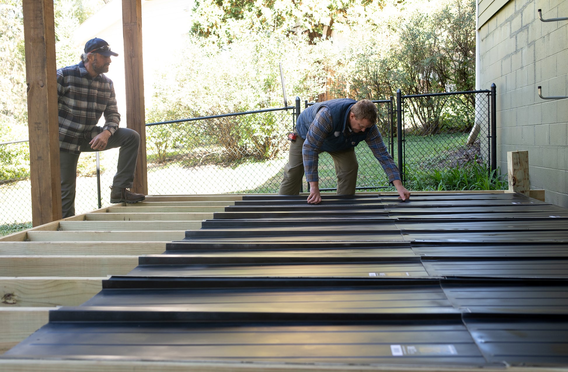 Two people installing UnderDeck Shields panels on the topside of a deck.