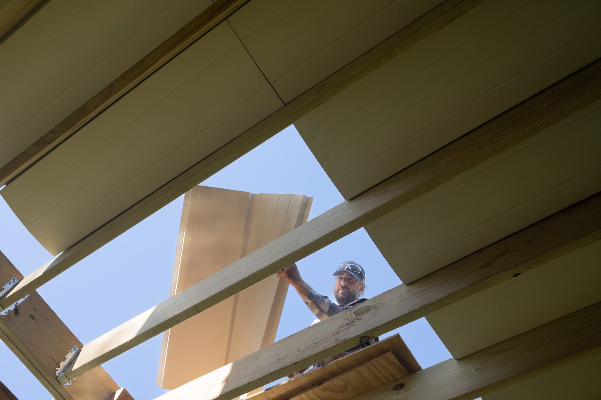 Person installing UnderDeck Shield panels on the topside of a deck