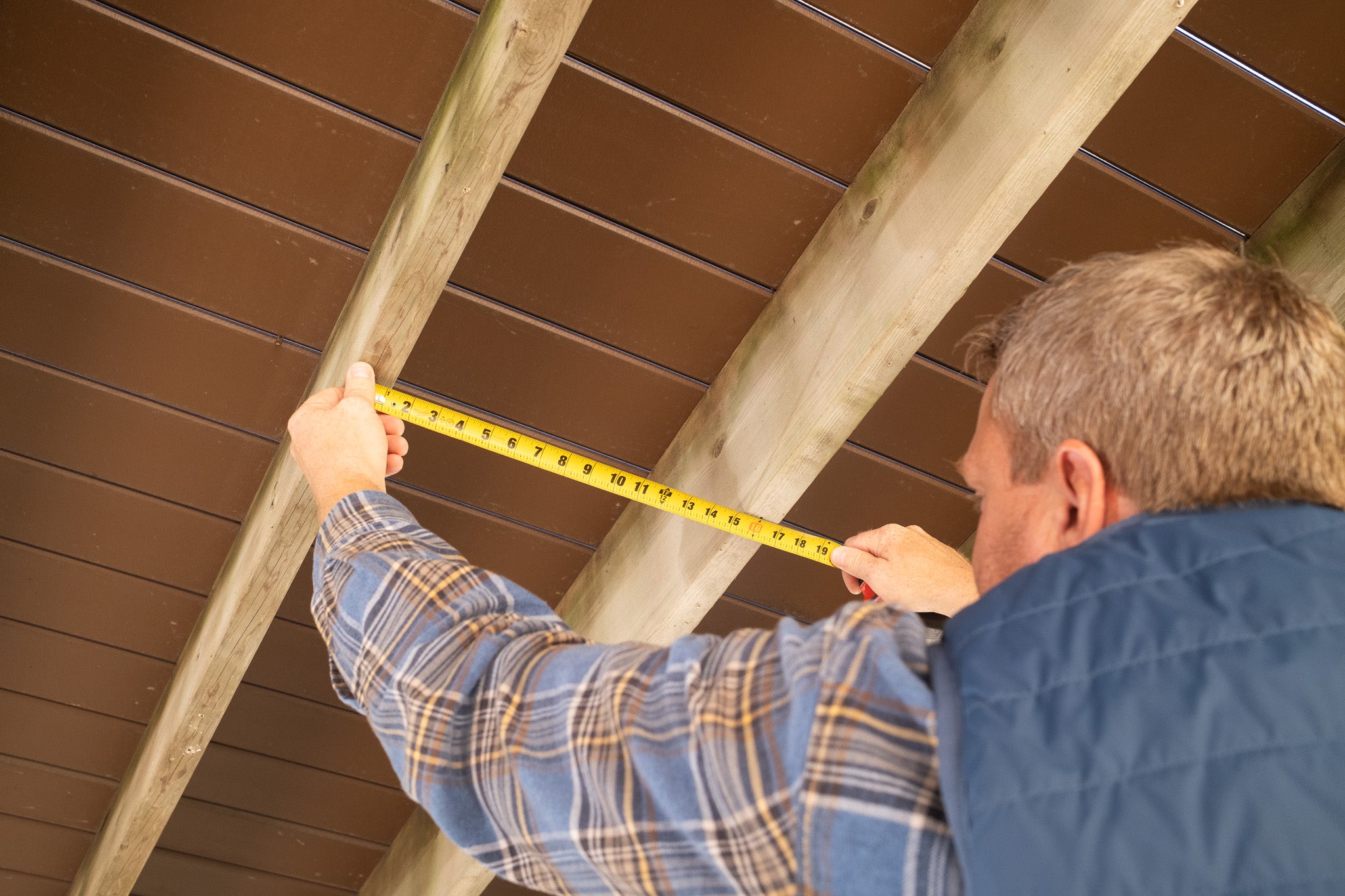 Person measuring joist distances.