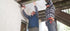 Two people installing UnderDeck Shields panels on the underside of a deck.