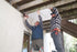 Two people installing UnderDeck Shields panels on the underside of a deck.