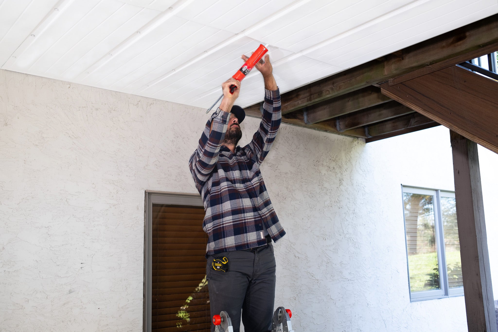 Person installing an UnderDeck Shields panel with caulk.