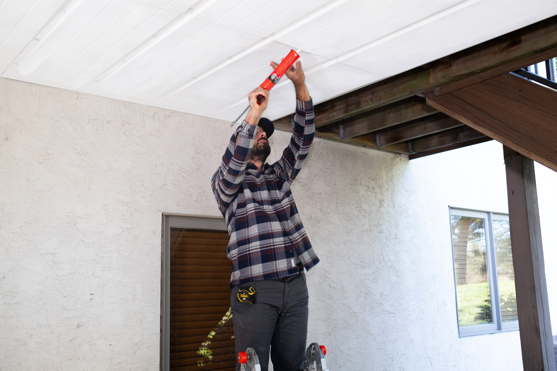 Person installing an UnderDeck Shields panel with caulk.