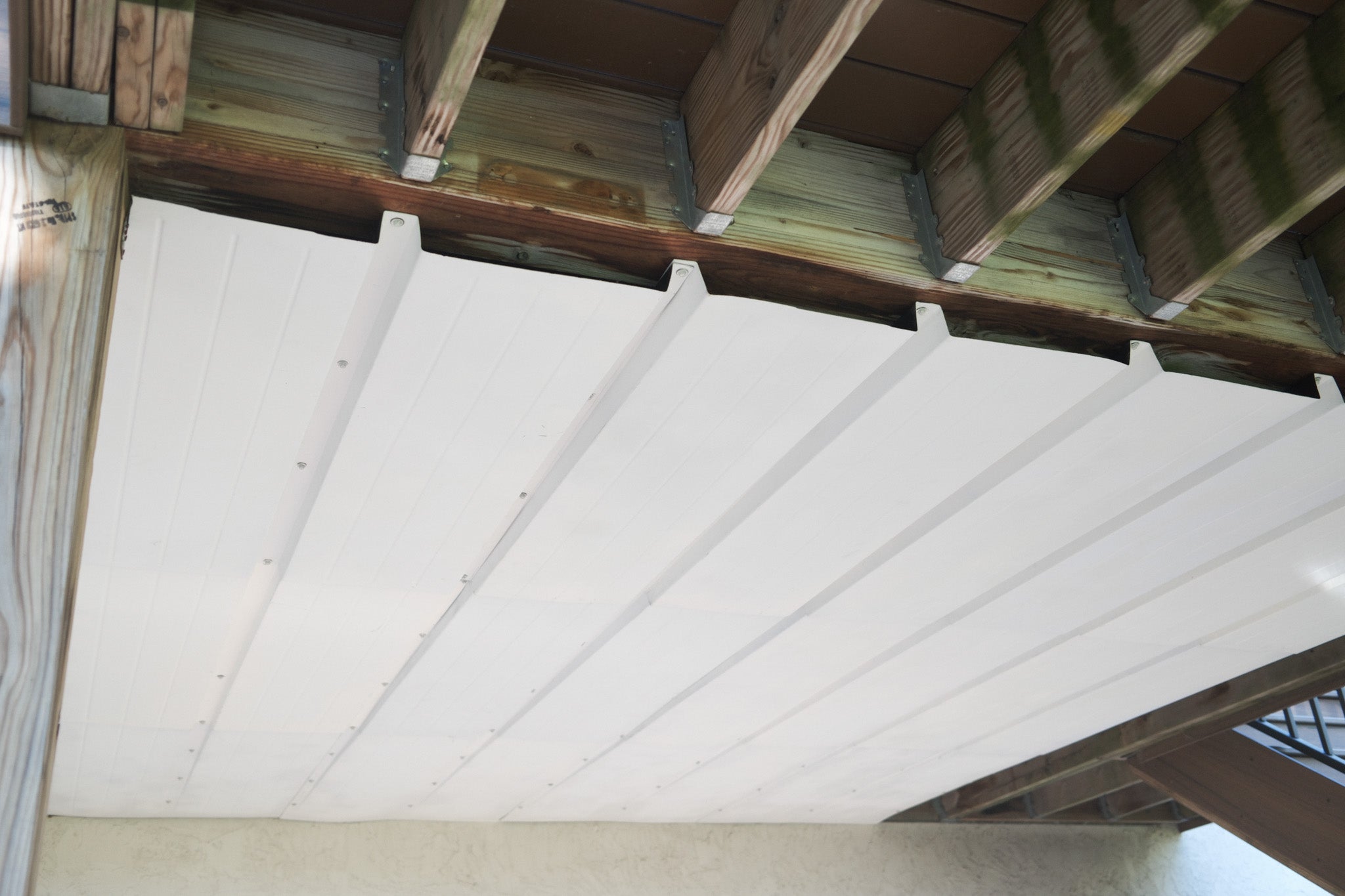 Installation of UnderDeck Shields panels on the underside of a deck.
